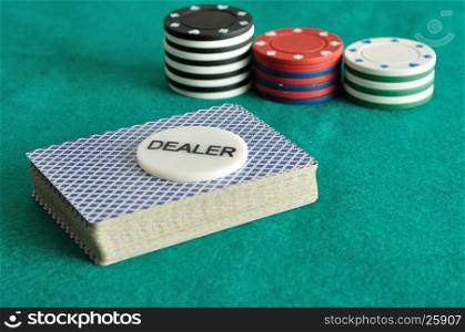 A deck of card with the dealer chip and some poker chips