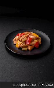 A delicious dish consisting of slices of chicken, sweet peppers and onions with salt and spices on a dark concrete background