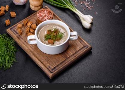 A delicious fresh, thick soup of mushroom puree with breadcrumbs, spices and herbs on a wooden board against a dark concrete background. Vegetarian cuisine. A delicious fresh, thick soup of mushroom puree with breadcrumbs, spices and herbs