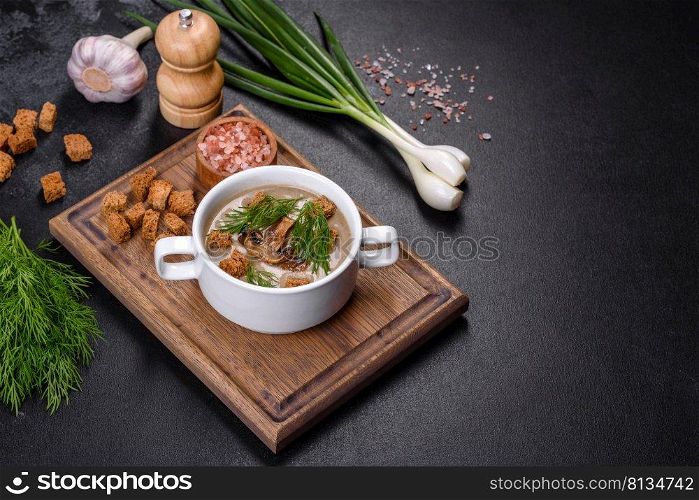 A delicious fresh, thick soup of mushroom puree with breadcrumbs, spices and herbs on a wooden board against a dark concrete background. Vegetarian cuisine. A delicious fresh, thick soup of mushroom puree with breadcrumbs, spices and herbs