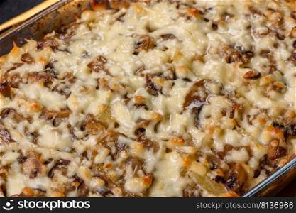 A delicious nutritious dish with meat, mushrooms, vegetables and potatoes, baked in a creamy sauce in an oven. Cooking home-cooked food. A delicious nutritious dish with meat, mushrooms, vegetables and potatoes, baked in a creamy sauce in an oven