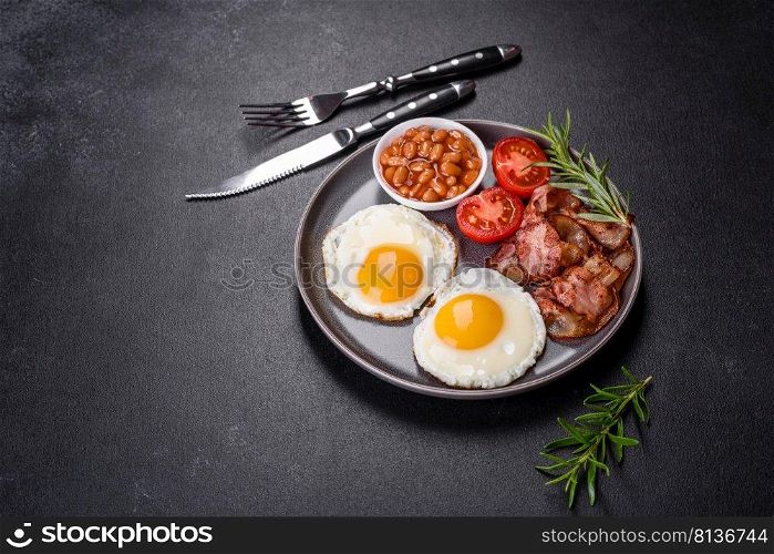 A delicious nutritious healthy breakfast with fried eggs, bacon, beans, a glass of juice, oat cookies, milk and jam. Healthy eating at the beginning of the day. A delicious nutritious healthy breakfast with fried eggs, bacon, beans, a glass of juice, oat cookies, milk and jam