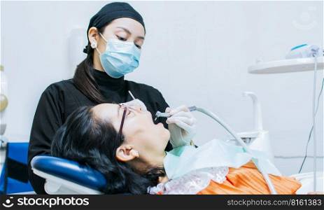 A dentist cleaning a patient’s mouth, a dentist cleaning a patient’s caries, a dentist cleaning a patient’s mouth, The stomatologist cleaning a patient’s teeth