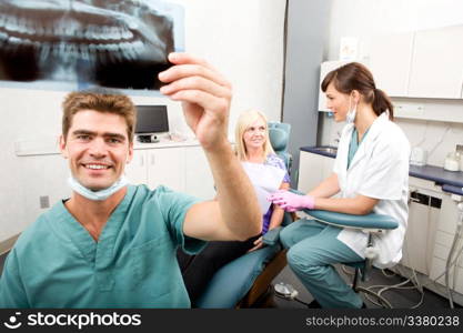 A dentist holding an x-ray while looking and smiling at the camera