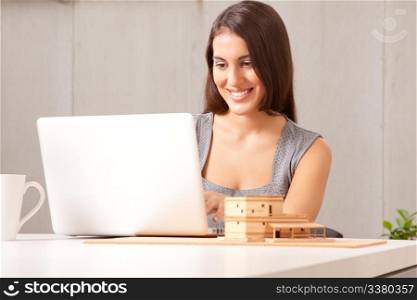 A designer or architect at desk with computer and model house