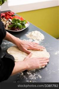 A detail image of a woman making pizza dough on the kitchen counter.