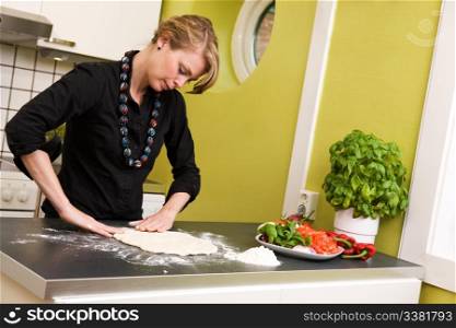 A detail image of a woman making pizza dough on the kitchen counter.