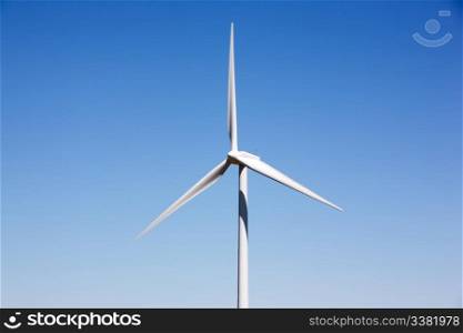 A detail of a wind turbine against a deep blue sky