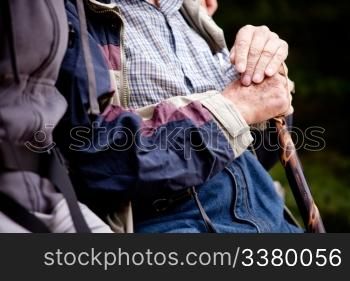 A detail of an elderly man outdoors with a walking stick