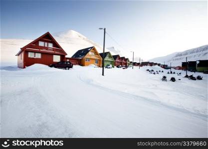 A detail of Longyearbyen, Svalbard, Norway. A row of houses and a mountain in the distance.