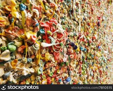 A detail view of a portion of the famous bubble gum wall in Post Alley near the Pike Place Market in Seattle. This landmark has built up layers of chewing gum over the years in colorful abstract pattern.