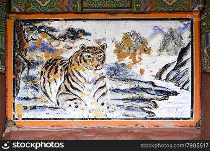 A detail view of a tiger painting on a panel on the exterior of one of the buildings in the Bongeunsa temple complex in Seioul, Korea. The image is weathred with certain portions chipped off.