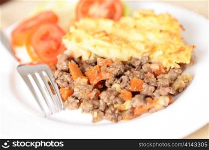 A dinner of shepherds pie or cottage pie and a salad with shallow depth of field