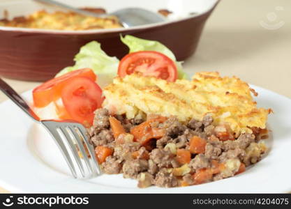 A dinner of shepherds pie or cottage pie and a salad with the serving dish in the background