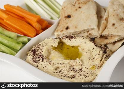 A dip tray with hummus, bread, carrot sticks, celery and cucumber.