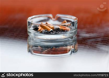 A dirty ashtray with cigarette ash and butts.. A dirty ashtray with cigarette ash and butts