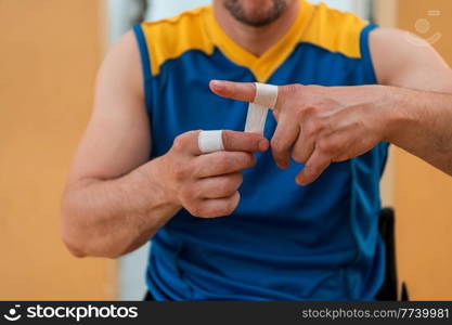 a disabled basketball player puts on a corset and bandages on his arms and fingers in preparation for a game in the arena. Selective focus . a disabled basketball player puts on a corset and bandages on his arms and fingers in preparation for a game in the arena