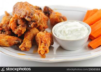 A dish of chicken hot wings and carrots with dipping sauce