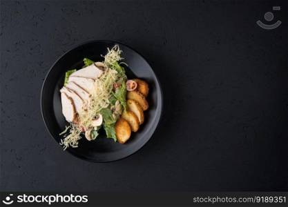 a dish of chicken on the black wooden surface, top view. a meat dish on a black surface
