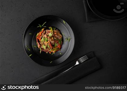 a dish of grilled meat on the black wooden surface, top view. a meat dish on a black surface