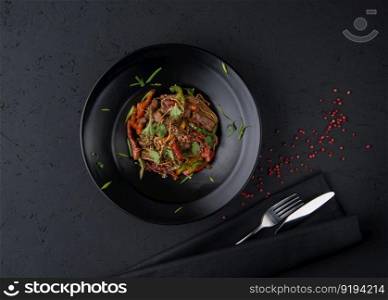 a dish of grilled meat on the black wooden surface, top view. a meat dish on a black surface