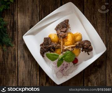 a dish of meat and potatoes in a plate on wooden background, top view. dish on a wooden surface