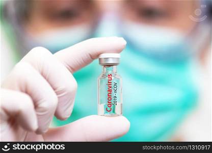 A doctor in medical gloves and mask holding an ampula with vaccine. Close up shot. Coronavirus, epidemic and medicine concept .. A doctor in medical gloves and mask holding an ampula with vaccine. Close up shot. Coronavirus, epidemic and medicine concept.
