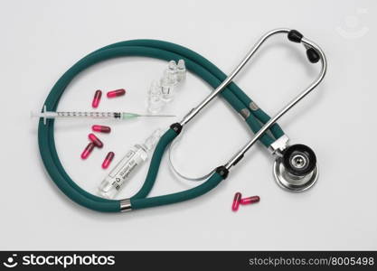 A doctors stethoscope with a syringe and drugs