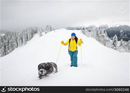 A dog and his mistress alone in the mountains with lots of snow.