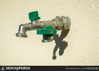 A double brass garden faucet mounted in the bright wall