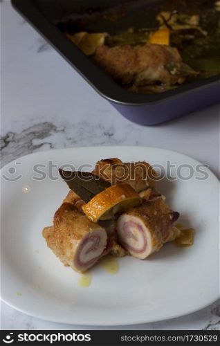 A drizzle of oil running down onto chicken rolls stuffed with cooked ham and smoked scamorza cheese