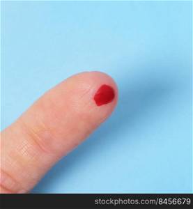 A drop of blood on a fingertip isolated on blue background. concept of diagnosis of diabetes.. A drop of blood on a fingertip isolated on blue background. concept of diagnosis of diabetes