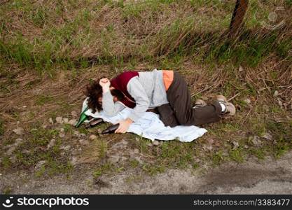 A drunk laying in the ditch with a number of bottles