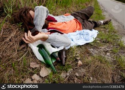 A drunk man laying in the ditch with beer bottles
