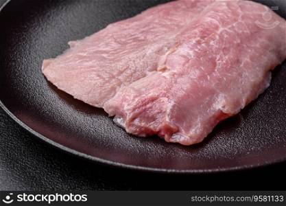 Aπece of fresh juicy raw pork with sa<, sπces and herbs on a dark concrete background