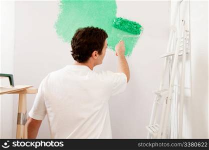 A faceless male painting a wall with a roller brush, home improvements