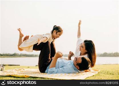 A family enjoys playful moments together. Father holds daughter high in air as she giggles and spreads her arms like wings, while mother watches with a smile outdoor. a precious moment of family fun