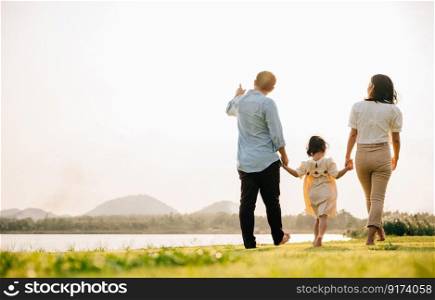 A family of four walking together in a beautiful park in Thailand, with a green nature background and a feeling of fun and excitement, Family day, back view