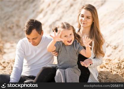 A family of three is sitting among mountains of sand.. A young family is sitting among the sandy mountains 3357.