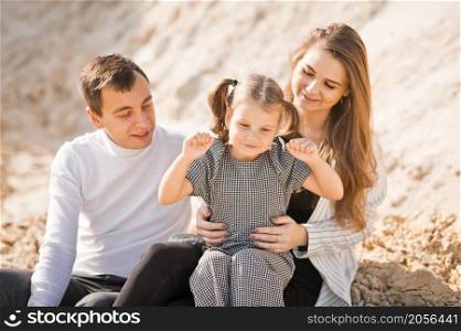 A family of three is sitting among mountains of sand.. A young family is sitting among the sandy mountains 3357.
