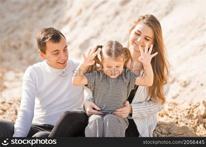 A family of three is sitting among mountains of sand.. A young family is sitting among the sandy mountains 3359.