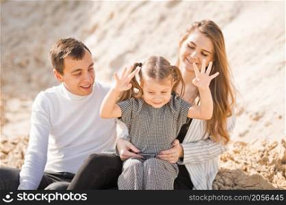 A family of three is sitting among mountains of sand.. A young family is sitting among the sandy mountains 3359.