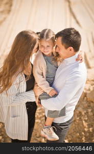 A family poses standing on a mountain of sand against the sky.. A young family with a daughter among the sand and blue sky 3306.