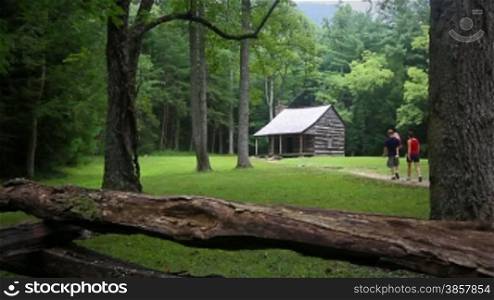 A family walking up a trail to visit a scenic historic cabin at Cades Cove in the Smokey Mountains
