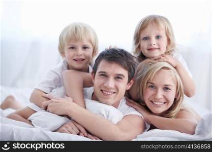 A family with two children on a bed in the bedroom