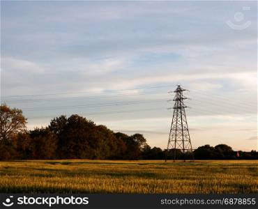 a farm field outside as the sunsets with a serene sky and a pylon wonderful and peaceful with no people