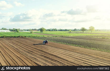 A farm tractor cultivates the soil in the field after harvest. Development of agricultural technologies. Loosening, improving soil quality. Food vegetable production. Sowing campaign