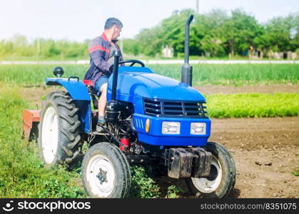 A farmer drives a tractor while working on a farm field. Loosening surface, cultivating the land. Farming, agriculture. Use of agricultural machinery and equipment to simplify and speed up work.