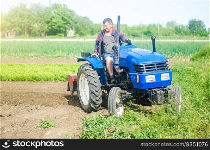 A farmer drives a tractor while working on a farm field. Loosening surface, cultivating the land. Farming, agriculture. Field preparation. Use of agricultural machinery and equipment to speed up work.