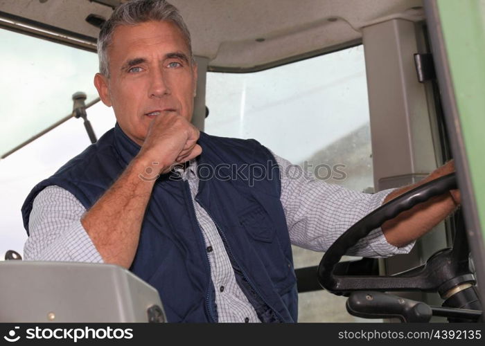 a farmer in a tractor cabin is driving